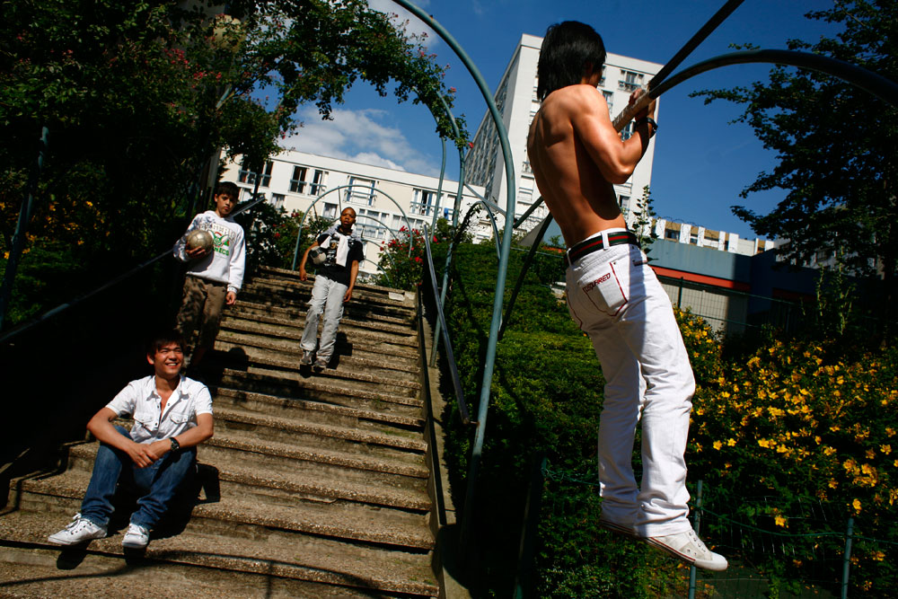 Des jeunes chinois du quartier font de la musculation au pied des tours, place Marcel Achard.