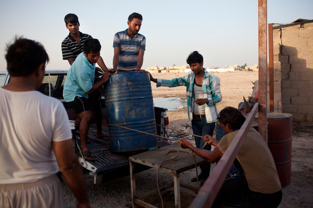 Le Camp Al Wakra, au milieu du désert n'a ni eau courante ni eau potable. Les ouvriers déchargent des barils d'eau, le soir, à la fin de leur journée de travail.