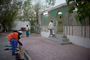 Camp Al Nakhla. Retour des ouvriers à la tombée du jour pour l'heure de la prière à la mosquée.